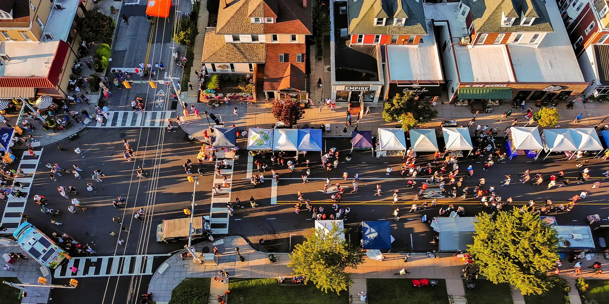 Aerial view of neighbors gathered at a small-town street festival with vendor tents and food trucks