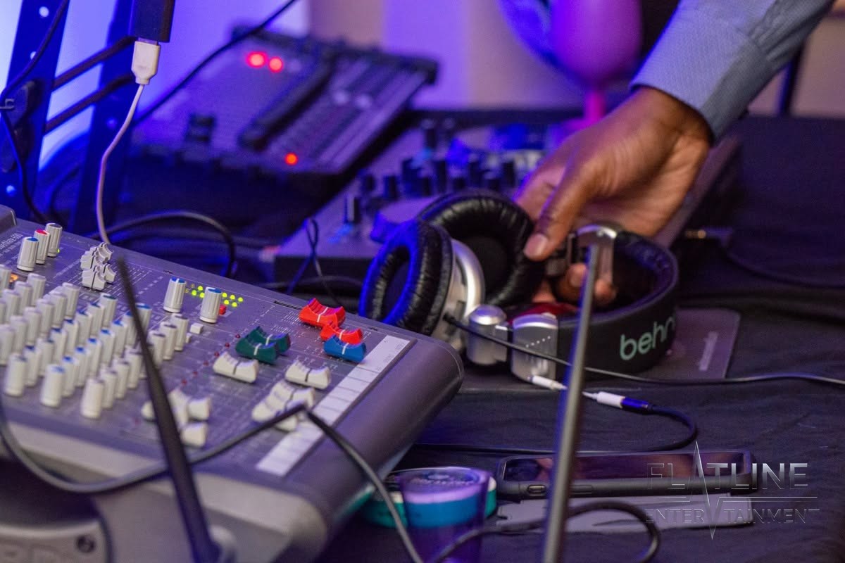 Hands working the DJ turntables and mixer up close