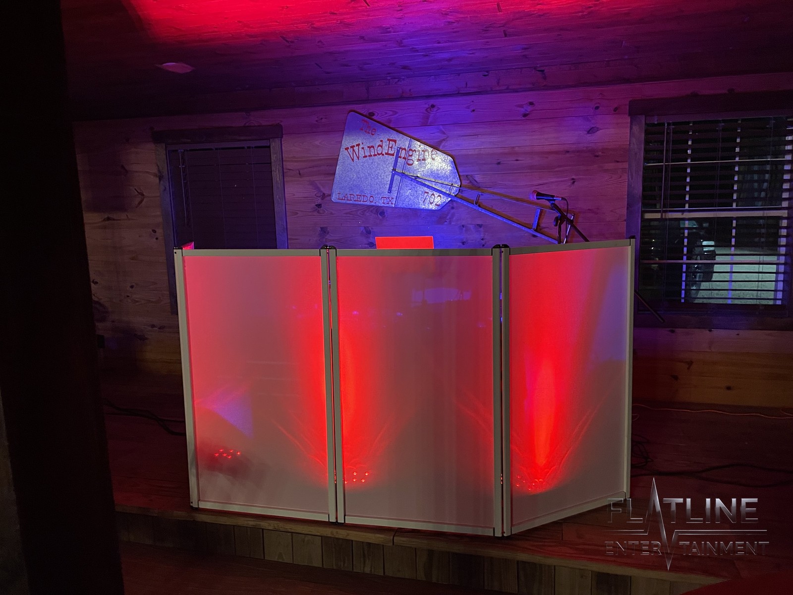 The Flatline DJ booth facade with illuminated red panels in a wood-paneled hall