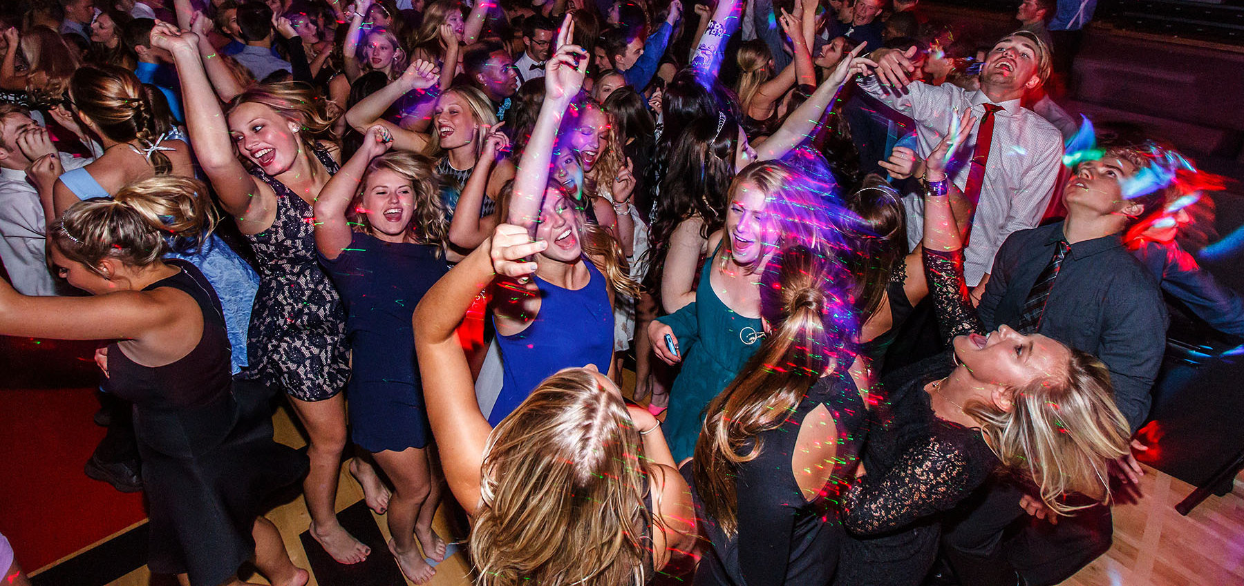 Students dancing under colorful party lights at a school dance