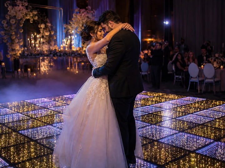 A bride and groom sharing their first dance on a sparkling lit floor
